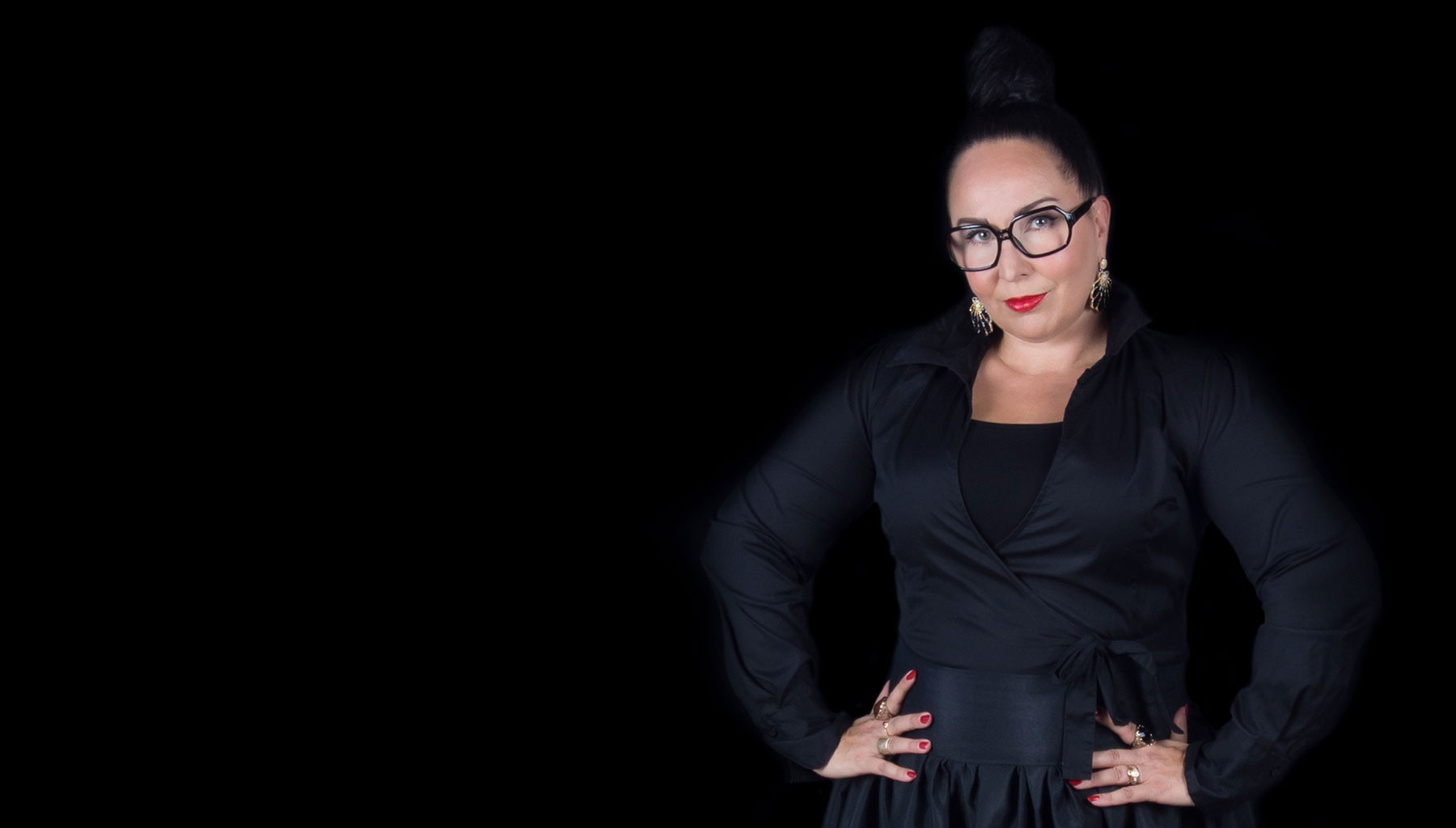 Storyteller Miia Pirinen in a black gown in a black background